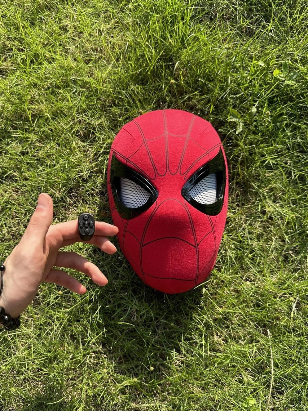 Red superhero mask on grass with a hand reaching towards it